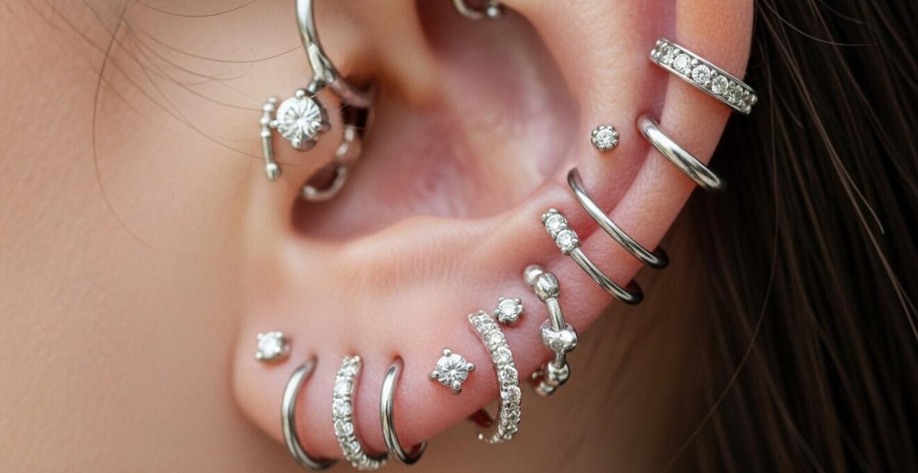 Oreille avec une composition créative et harmonieuse de piercings colorés et variés